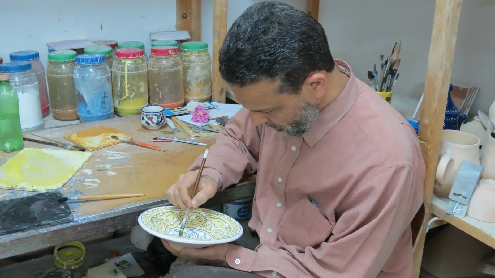 A ceramist painting a plate in a Nabeul pottery workshop